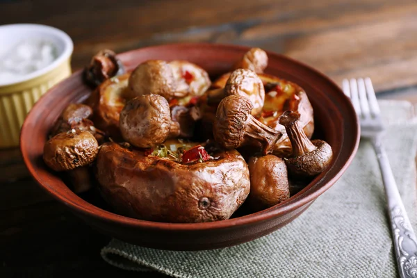 Baked potatoes with mushrooms in bowl and sauce on table close up — Stock Photo, Image