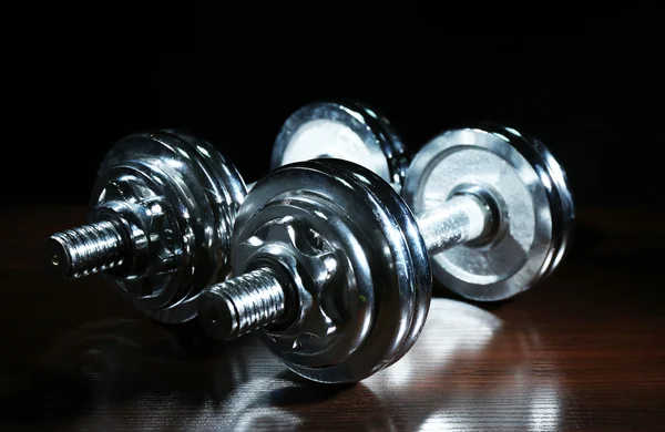 Dumbbells on wooden floor, on dark background — Stock Photo, Image