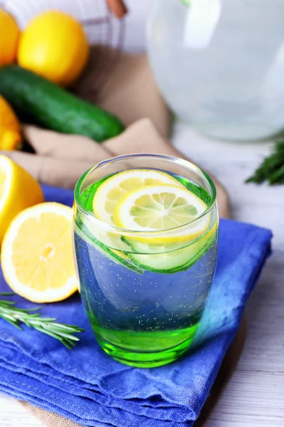 Friskt vatten med citron och gurka i glas på servett på träbord, närbild — Stockfoto