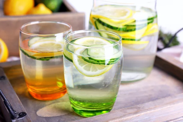 Fresh water with lemon and cucumber in glassware in wooden tray, closeup — Stock Photo, Image