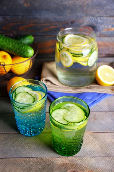 Acqua dolce con limone e cetriolo in vetreria su fondo legno — Foto Stock