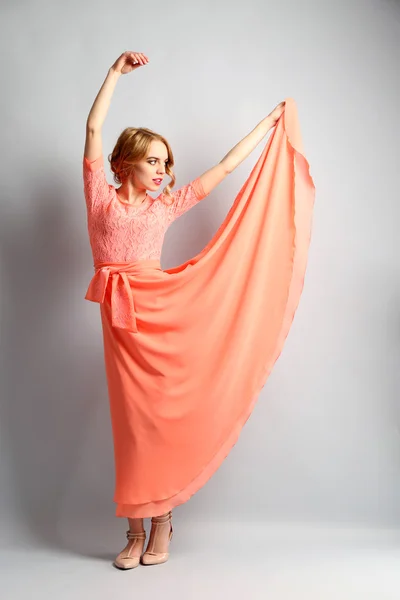 Hermosa mujer joven en vestido de color posando sobre fondo claro —  Fotos de Stock