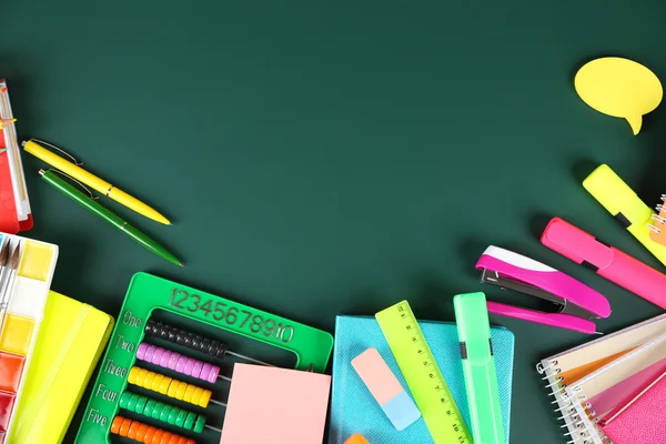 Bright school supplies on blackboard background — Stock Photo, Image