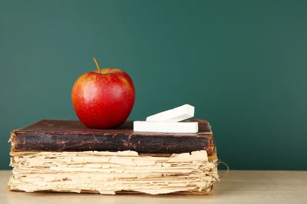 Alte Bücher, Apfel und Kreide auf Tafel-Hintergrund — Stockfoto