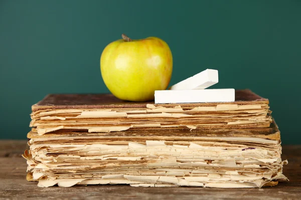 Alte Bücher, Apfel und Kreide auf Tafel-Hintergrund — Stockfoto