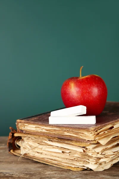 Vecchi libri, mela e gesso su sfondo lavagna — Foto Stock