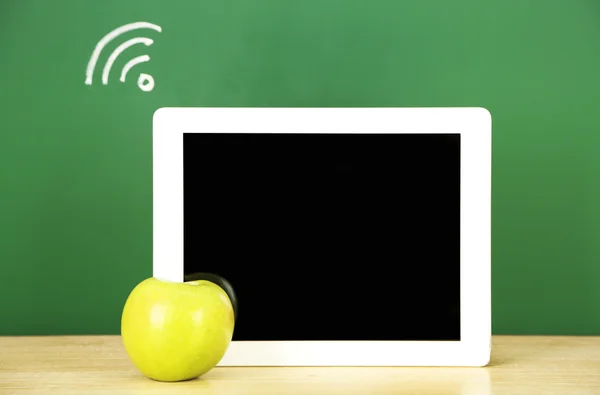 Tablet on table, on green blackboard background — Stock Photo, Image