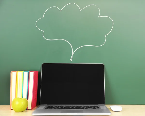 Laptop op tafel, op groene krijtbord achtergrond — Stockfoto