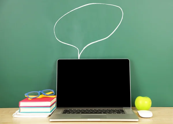 Laptop on table, on green blackboard background — Stock Photo, Image