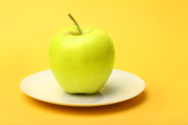 Apple on saucer on color background — Stock Photo, Image