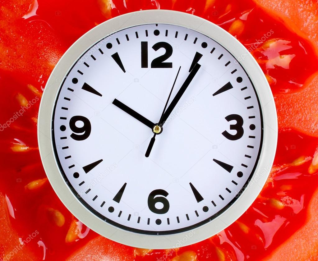 Food clock with tomato as background. Healthy food concept