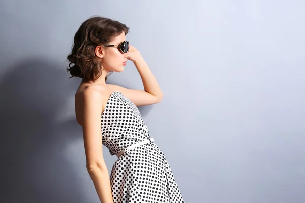 Porträt des schönen Modells im Punktekleid mit Sonnenbrille auf grauem Hintergrund — Stockfoto