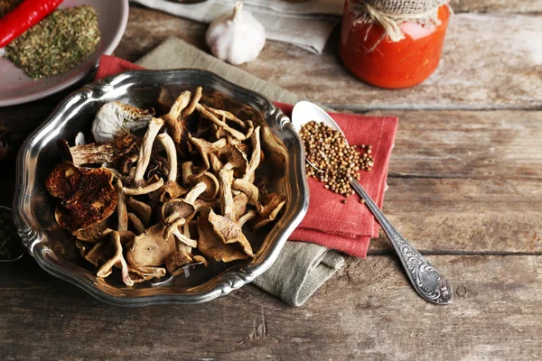 Сушеные грибы в металлическом лотке со специями на деревянном фоне — стоковое фото