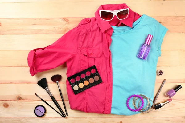 Female shirt and cosmetics on wooden table, top view — Stock Photo, Image