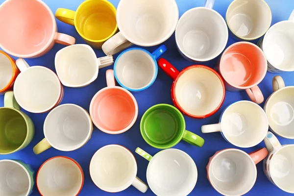 Група барвистих чашок на кольоровому столі, вид зверху — стокове фото