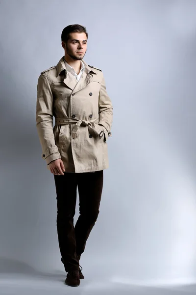 Jovem de casaco sobre fundo cinza — Fotografia de Stock