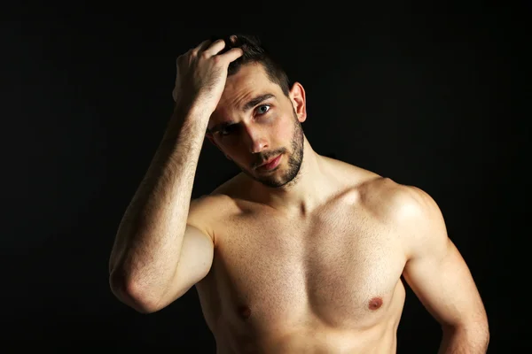 Muskulöser junger Mann auf schwarzem Hintergrund — Stockfoto