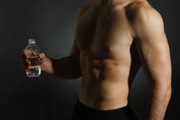 Muscle jeune homme tenant bouteille d'eau — Photo