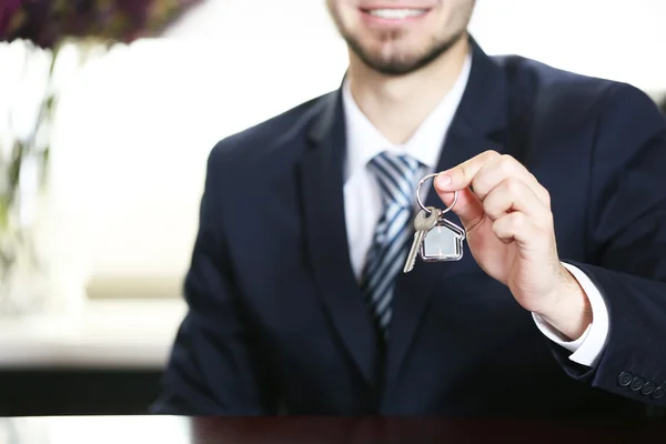 Empresario con llaves en la mano en la oficina sobre fondo borroso — Foto de Stock