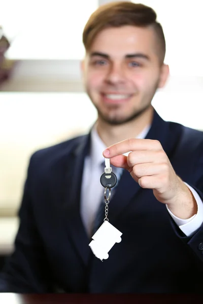 Portret van zakenman met sleutels in hand in kantoor op onscherpe achtergrond — Stockfoto