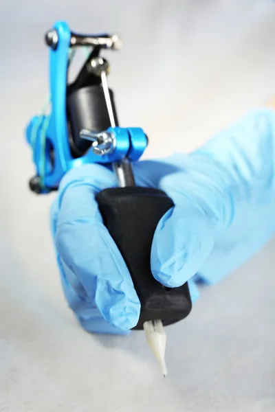 Tattoo machine in hand van Tattoo kunstenaar, close-up. op lichte achtergrond — Stockfoto