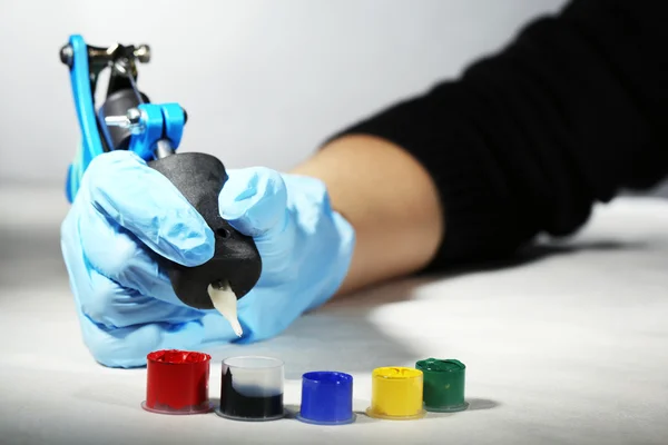 Tattoo machine in hand of Tattoo artist, close-up. on light background — Stock Photo, Image