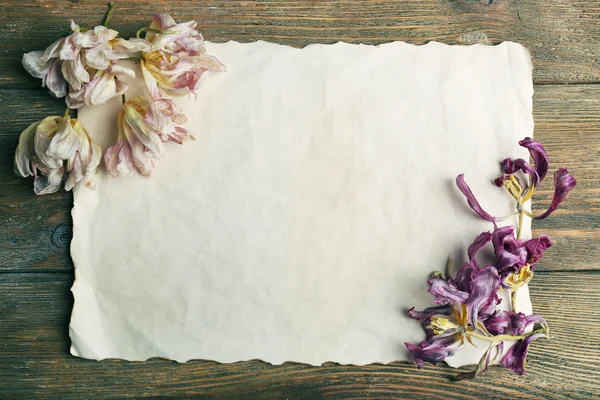 Gedroogde bloemen op vel papier op houten tafel, bovenaanzicht — Stockfoto