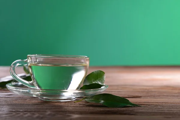 Taza de té verde en la mesa sobre fondo verde —  Fotos de Stock