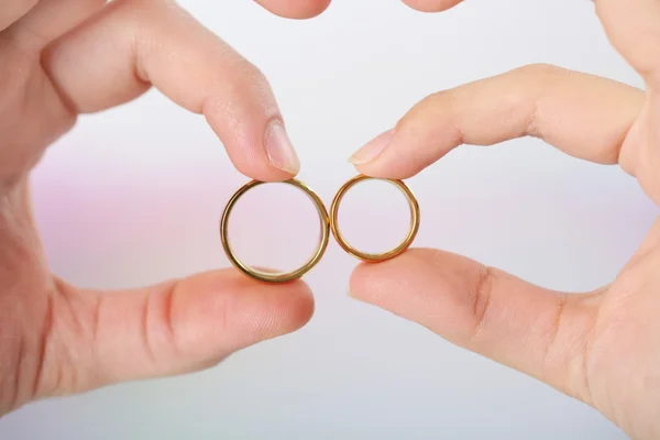 Mulher e homem segurando anéis de casamento, close-up, no fundo brilhante — Fotografia de Stock