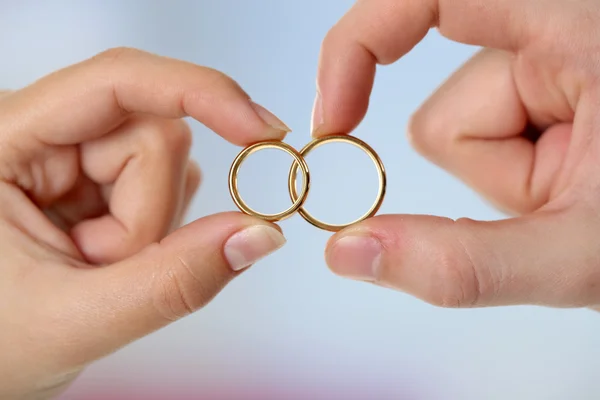 Mulher e homem segurando anéis de casamento, close-up, no fundo brilhante — Fotografia de Stock