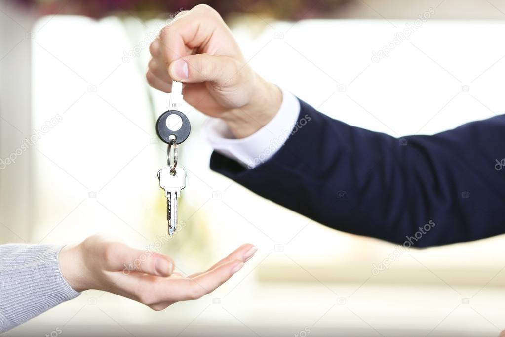 Hand of businessman giving keys to female hand