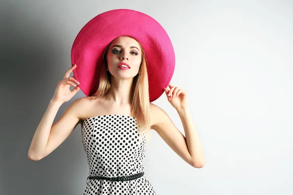 Retrato de modelo joven con sombrero rosa sobre fondo gris — Foto de Stock