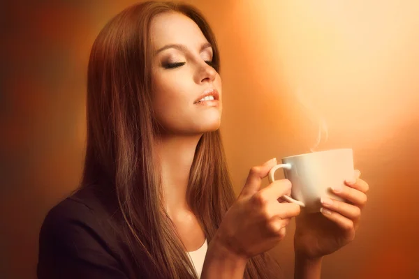 Piękna młoda kobieta z filiżanką kawy na brązowym tle — Zdjęcie stockowe