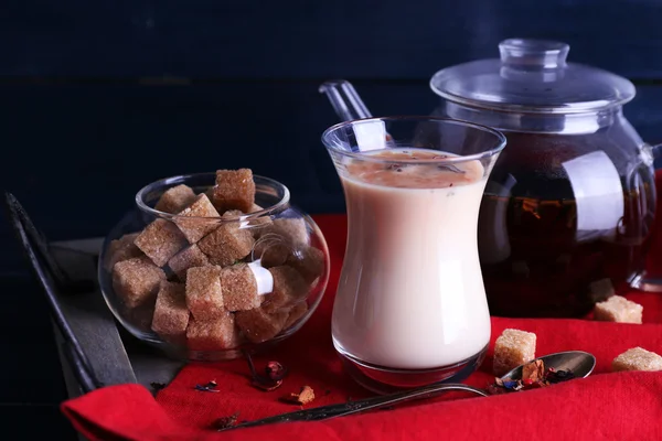 Svart te med melk og klumpsukker på trebrett med serviett og bakgrunn av treplanker – stockfoto