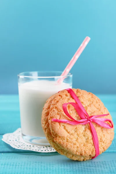 Chutné cookies a sklenici mléka na barevné dřevěné pozadí — Stock fotografie