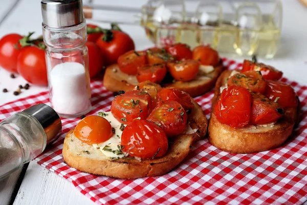 Fette di pane bianco tostato con burro e pomodori in scatola su sfondo tavole di legno di colore — Foto Stock