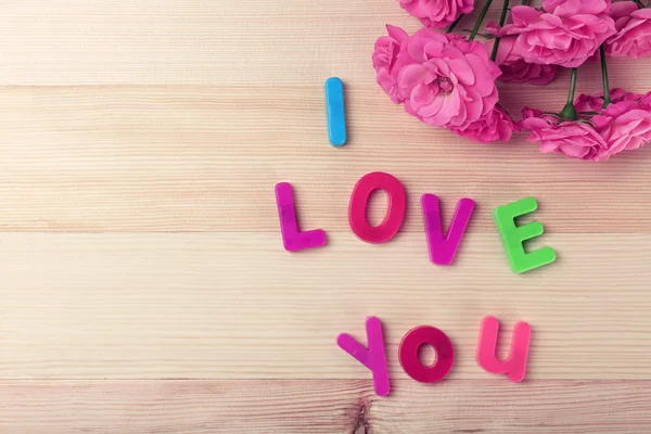 Mooie rozen met zin "I Love You" op houten tafel achtergrond — Stockfoto