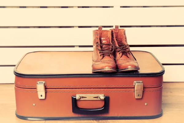 Vintage koffer met mannelijke schoenen op houten vloer en kleur planken achtergrond — Stockfoto