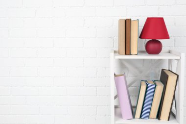 Kitap ve tuğla duvar arka lamba ile ahşap raf