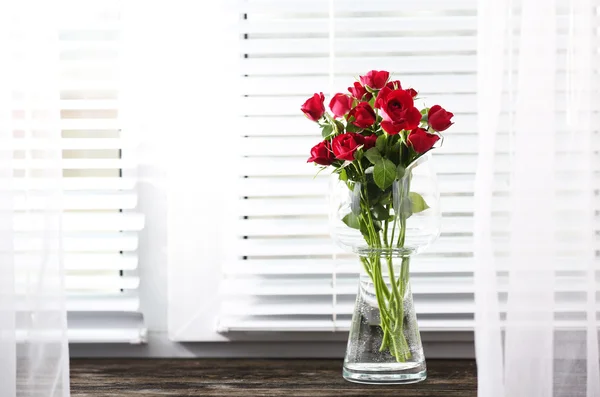 Rosas rojas en jarrón de vidrio sobre fondo alféizar de ventana — Foto de Stock