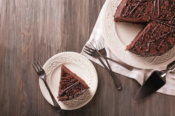 In Scheiben geschnitten köstlichen Schokoladenkuchen mit Besteck auf Holztischhintergrund — Stockfoto