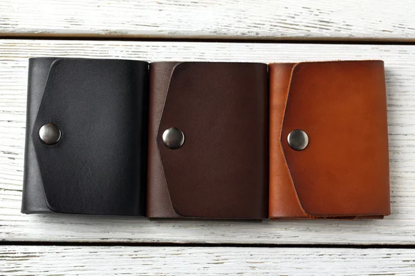 Tři ručně vyrobené kožené peněženky člověka na bílém pozadí dřevěná — Stock fotografie