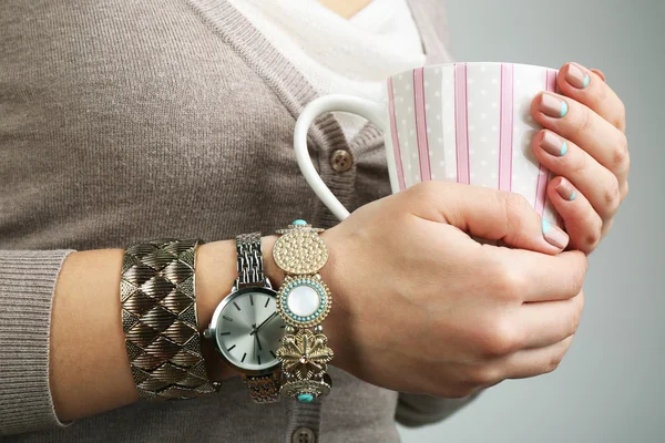 Pulseras con estilo y reloj en mano femenina sobre fondo brillante — Foto de Stock