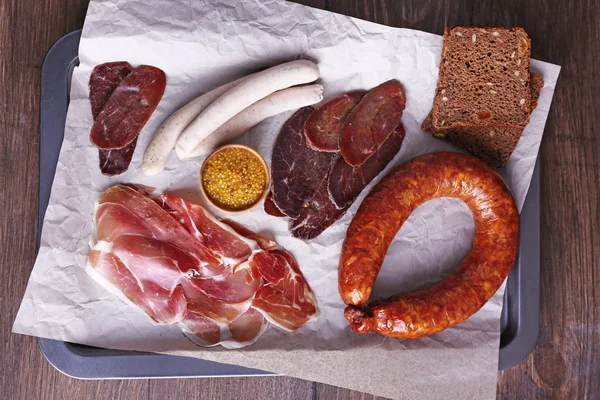 Assortment of deli meats on parchment on wooden table background — Stock Photo, Image