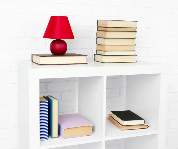 Estante de madera con libros y lámpara sobre fondo de pared de ladrillo —  Fotos de Stock