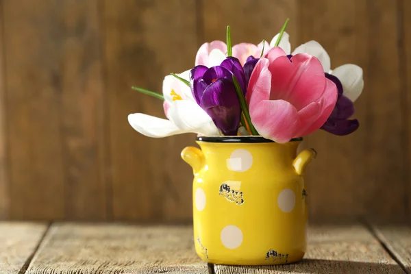 Vackra vårblommor i gula kruka på trä bakgrund — Stockfoto