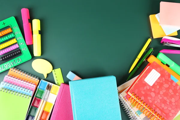 Bright school supplies on blackboard background — Stock Photo, Image