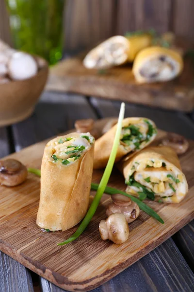 Panquecas com cogumelos cremosos na tábua de corte na mesa de madeira, close-up — Fotografia de Stock