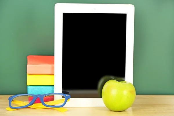 Tablet on table, on green blackboard background — Stock Photo, Image
