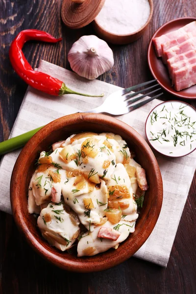 Gebratene Knödel mit Zwiebeln und Speck in der Pfanne, auf Holztischhintergrund — Stockfoto